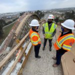 USDOT FRA Deputy Administrator Amit Bose conferring with Authority experts while standing atop the falsework that will help cast one of the concrete arches of the Cedar Viaduct which will carry trains at more than 200 miles per hour over State Route 99, with the structure's other arches behind him.
